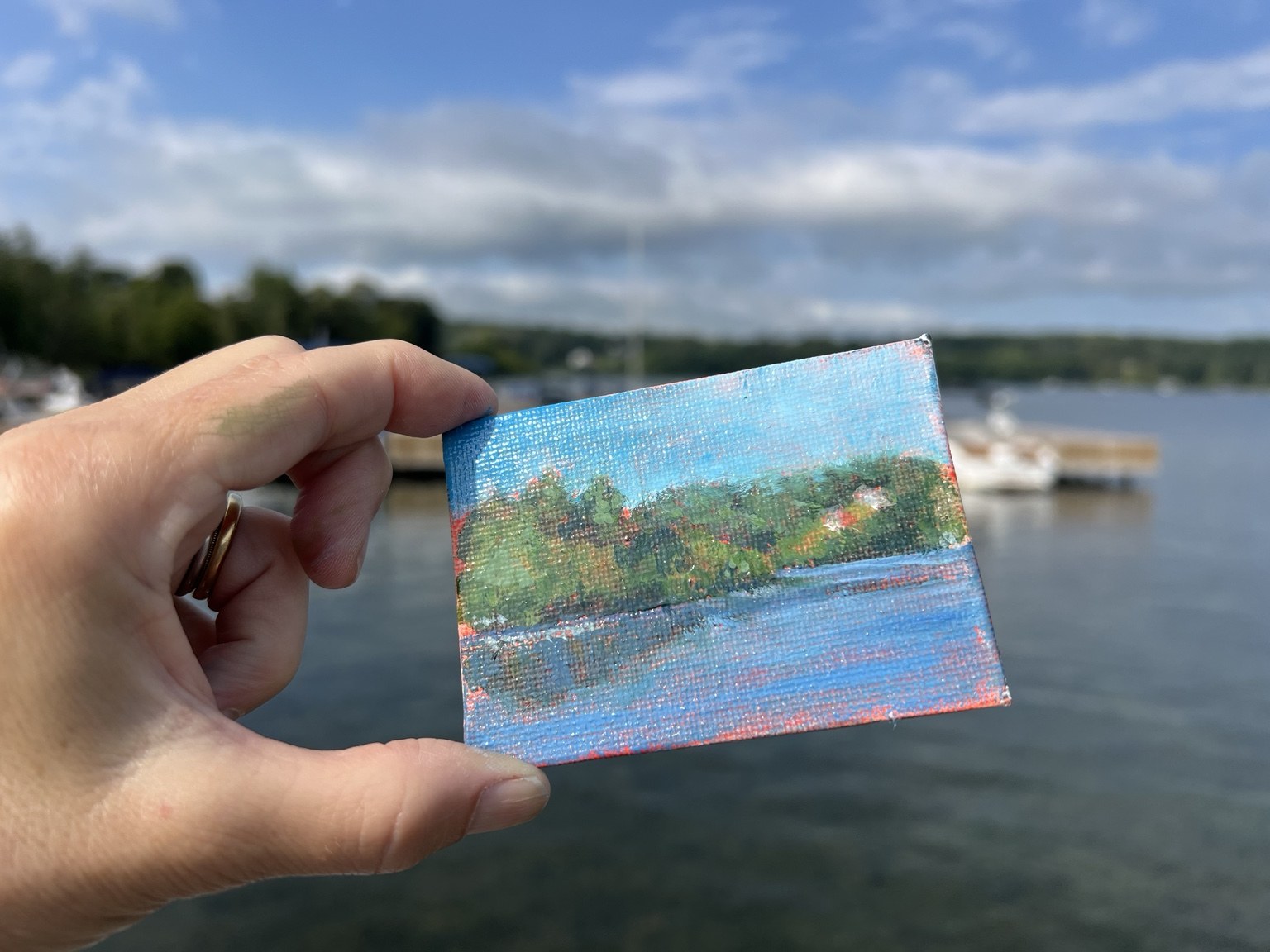 A small lake painting held up against its view